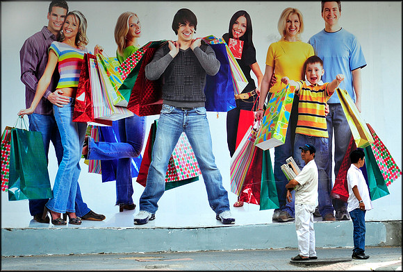 Western shoppers appear as giants against street sellers outside Eden Building