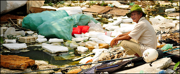 Man Fishing in Polluted River